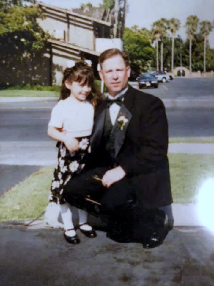 Jennifer as a small girl with her father Paul, dressed up outside a wedding.