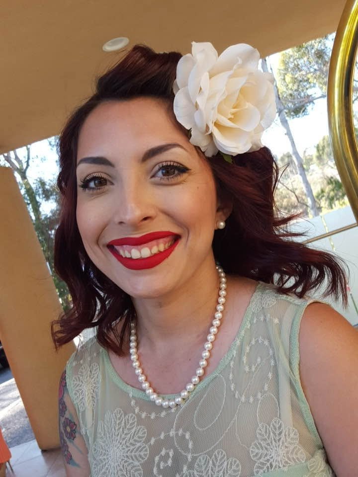 Jennifer Baxter smiling, a cream rose in her hair and a string of pearls at her neck.