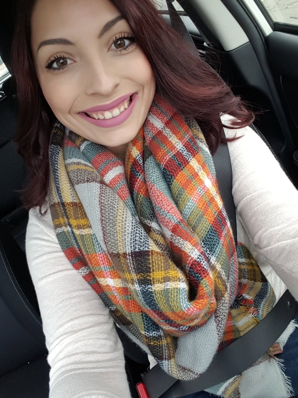 Jennifer smiling in a plaid autumn scarf.