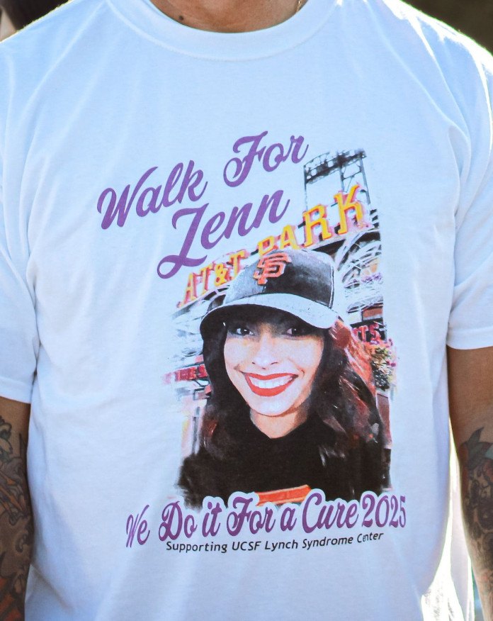 The 2025 Walk for Jenn shirt: Jennifer in her Giants cap at the ballpark, with purple script reading Walk For Jenn and We Do it For a Cure 2025.